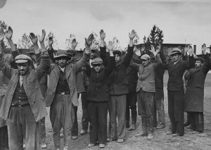 Polish and Jewish citizens of Aleksandrów Kujawski, Poland hold their arms in the air during their arrest by German soldiers, September 1939. Photo credit: USHMM #08765