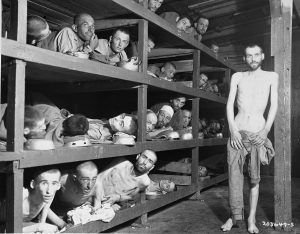 Former prisoners of the “little camp” in the Buchenwald concentration camp in Germany stare out from the wooden bunks in which they slept three to a “bed.” Elie Wiesel is pictured in the second row of bunks, seventh from the left, next to the vertical beam, April 16, 1945. Photo credit: USHMM #74607