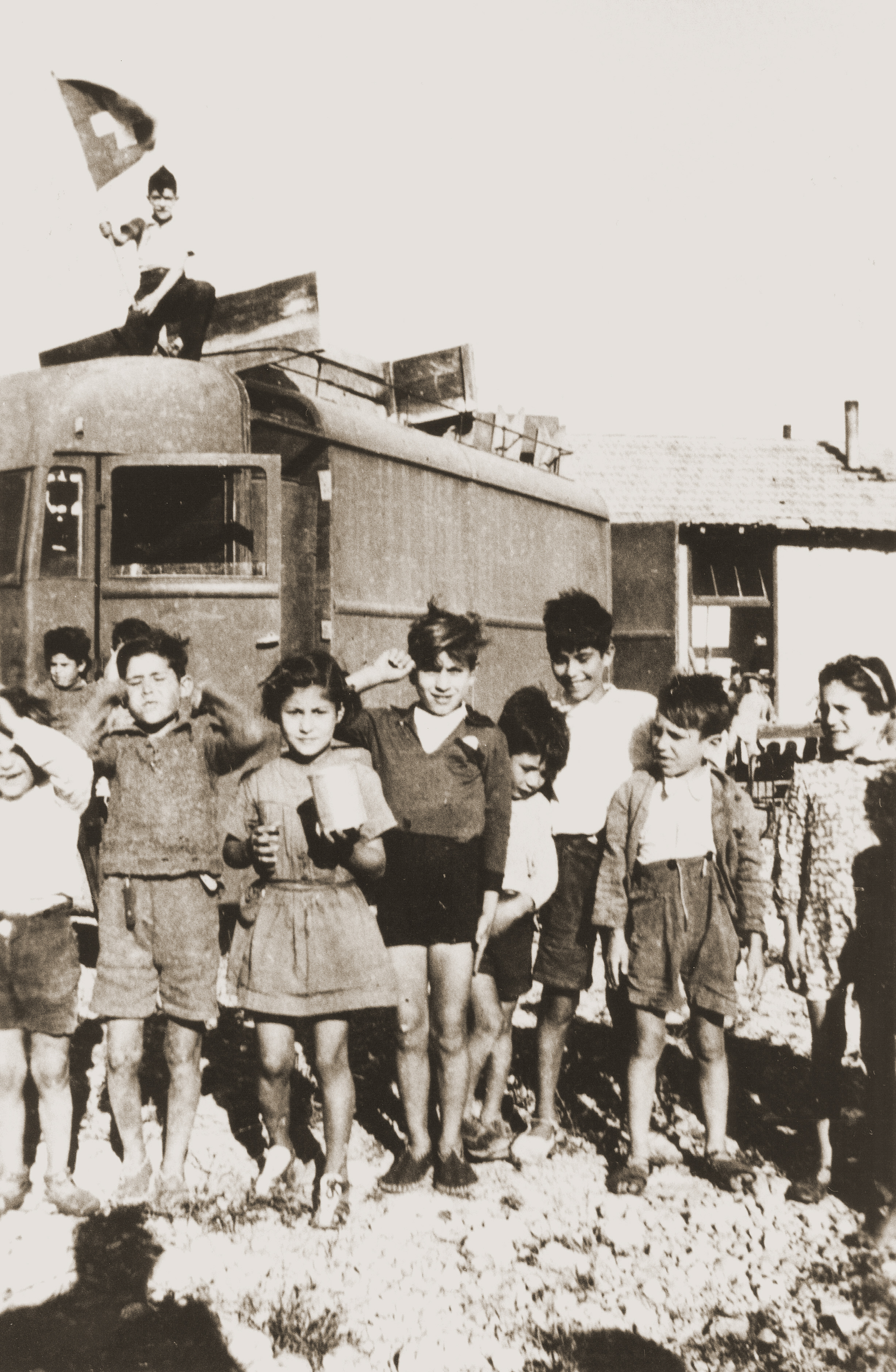 Children in Rivesaltes pose beneath a Swiss flag on the occasion of the Secours Suisse moving its quarters in the camp