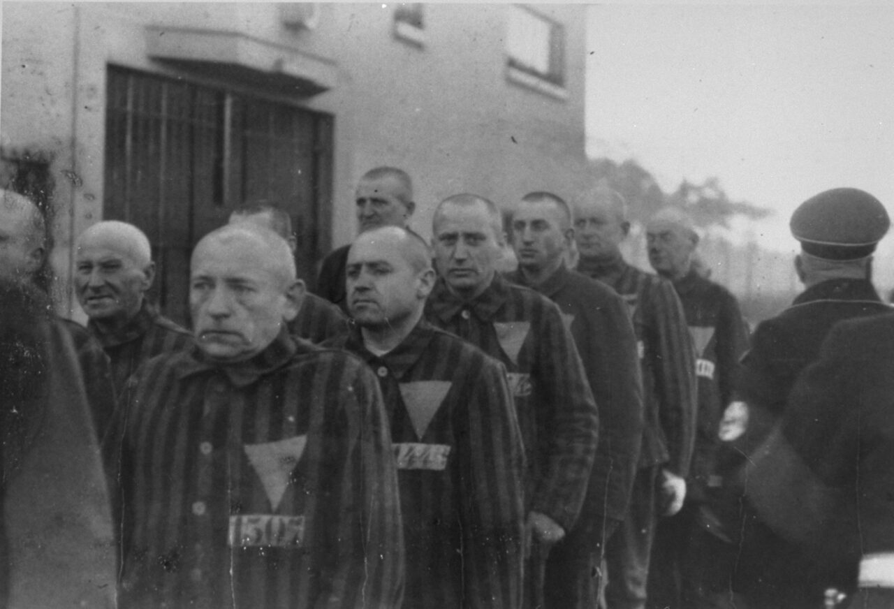 Uniformed prisoners are assembled in front of a Nazi guard at the Sachsenhausen concentration camp near Oranienburg, Germany, 1938. Photo credit: USHMM #76278
