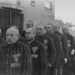 Uniformed prisoners are assembled in front of a Nazi guard at the Sachsenhausen concentration camp near Oranienburg, Germany, 1938. Photo credit: USHMM #76278